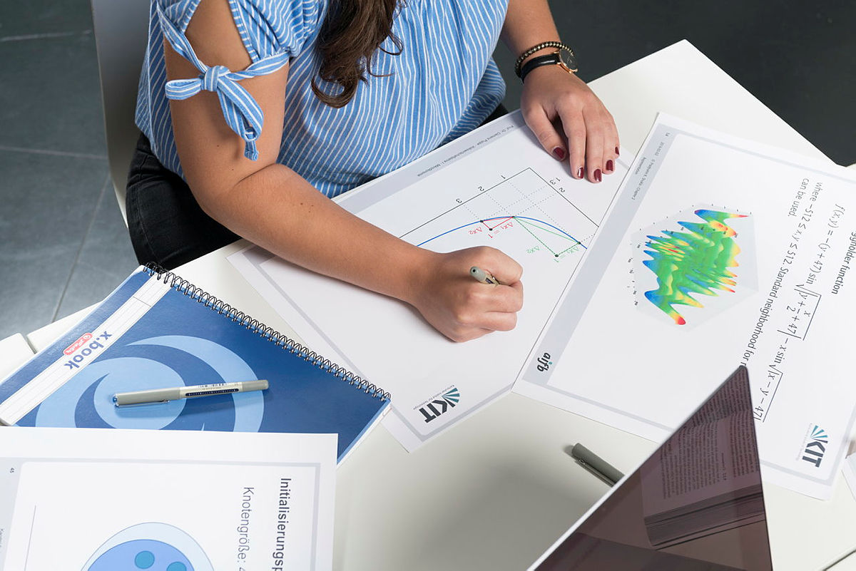 Person schreibt Notizen auf wissenschaftliches Diagramm auf einem Tisch.